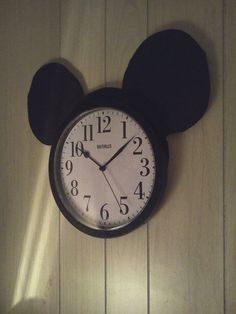 a mickey mouse clock is hanging on the wall with its ears up and hands down