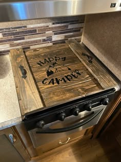 a stove top oven sitting inside of a kitchen next to a countertop with a wooden sign on it