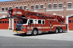 a large red fire truck parked in front of a building with a ladder on it's side