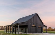 a black barn with a covered porch in the evening