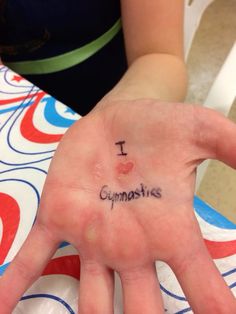 a person's hand with the word i love gymnastics written on it, in front of her