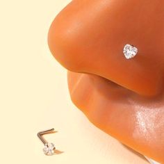 a pair of diamond studs sitting on top of an orange piece of cloth next to a nose ring