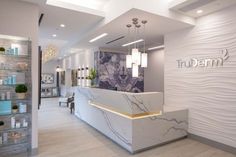 the interior of a salon with white marble counter tops and lights hanging from the ceiling