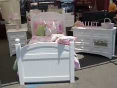 there are many white beds and dressers on display at the flea market, including one for sale