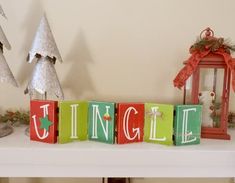 the word jungle spelled with blocks in front of christmas trees and lantern holders on a mantle