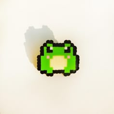 an image of a green pacman brooch on a white surface with shadow coming from the back