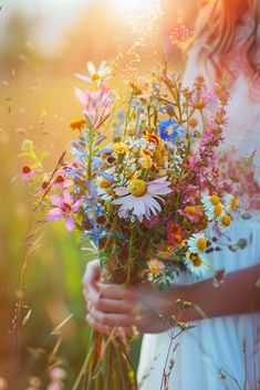 a woman holding a bouquet of wildflowers in her hands