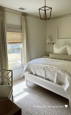 a white bed sitting next to a window in a bedroom