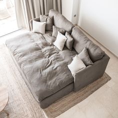 a large gray couch sitting on top of a living room floor next to a window