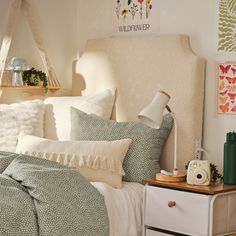 a white bed topped with lots of pillows next to a night stand and nightstands