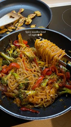 a pan filled with noodles and vegetables on top of a stove next to a spatula