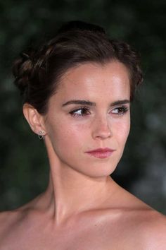 a close up of a person wearing a strapless top and hair in a bun