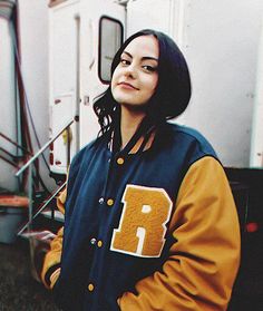 a woman standing in front of a trailer wearing a jacket with the letter r on it