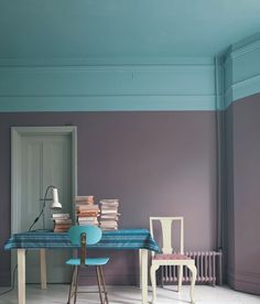 a room with two chairs and a table covered in books on top of the floor