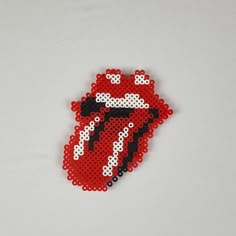 a red and white beaded brooch with the rolling stones on it's side