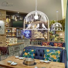 the interior of a restaurant with blue couches and tables in front of a birdcage