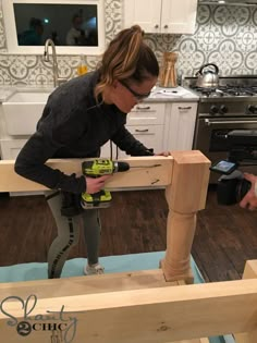 a woman using a driller on wood in a kitchen