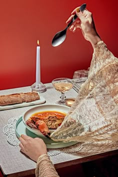 a woman sitting at a table with a plate of food in front of her and a candle