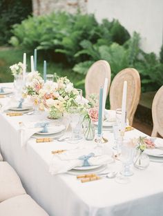 a table set with plates, candles and flowers on it for a formal dinner party