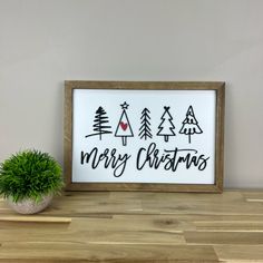 a wooden sign that says merry christmas next to a potted plant on a table