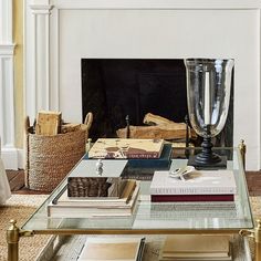 a coffee table with books and a vase on it in front of a fire place