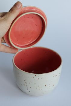 a hand is holding a red and white bowl