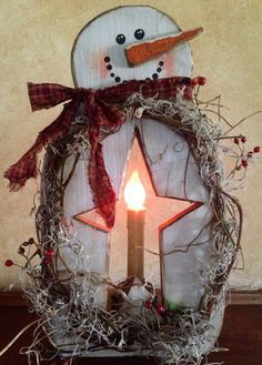 a snowman candle holder with a red ribbon around it and a star on top