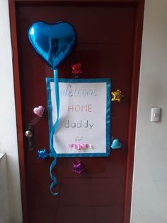 a welcome home door decorated with balloons and streamers for the child's birth