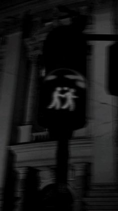 a black and white photo of a clock tower in the dark with blurry background