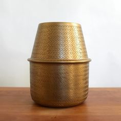 a gold vase sitting on top of a wooden table