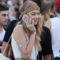 a woman talking on a cell phone while wearing a bandana and carrying a purse