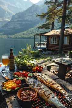 an outdoor grill with fish and vegetables on it next to a lake in the background