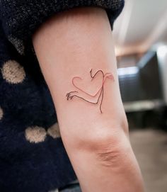 a woman's arm with a small heart tattoo on the left side of her arm