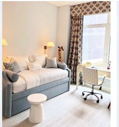 a living room with a couch, chair and desk next to a window in the corner