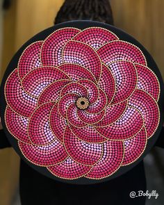 a woman is holding a pink and black plate with an intricate design on the front