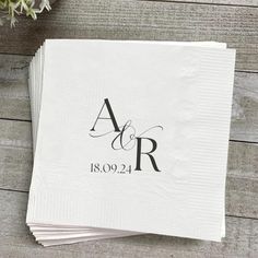 wedding napkins with the initials and date printed on them, sitting on a wooden table