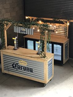 an outdoor bar with lights and vines growing on the top, in front of a brick wall