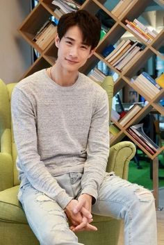 a man sitting in a chair next to a book shelf