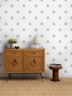 a wooden cabinet sitting next to a lamp on top of a table in front of a wall