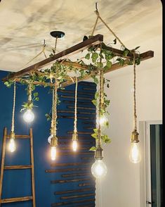 several light bulbs hanging from a wooden beam with plants growing on them and some ladders in the background