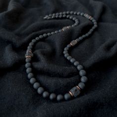 A grounding stone, Onyx is believed to absorb negative energies, alleviates worries and tensions, and eliminates confusion. It helps in being structured and letting go of unhappy thoughts. There is 1 accent cube Lava Stone bead, which is repeated multiple times for Balance. A grounding stone, Lava Stone is believed to provide stability during times of change and encourages strength and courage. It promotes change where needed for behavioral issues and enhances fertility. This necklace has an ela Men Necklace With Stone, Men’s Necklace Layering, Mens Stone Necklace, Men Crystal Necklace, Black Necklace Men, Men’s Beaded Necklace, Necklace For Men Aesthetic, Men Boho, Masculine Jewelry