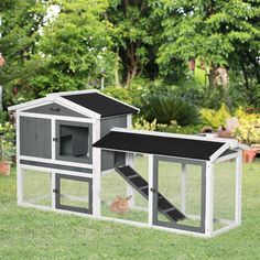 a rabbit house with a cat inside and stairs leading up to the roof, on grass in front of trees