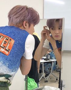 a boy is looking at his reflection in the mirror