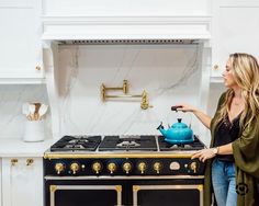 a woman standing in front of an oven with a tea kettle on the burner