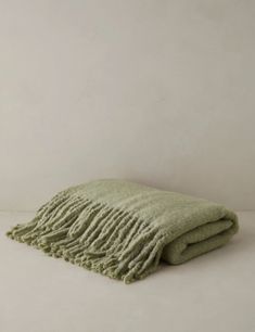 a green blanket folded on top of a white table