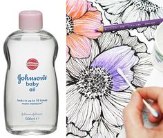 someone is drawing flowers on the paper next to a bottle of baby oil and a marker