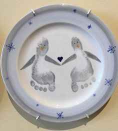 two penguins holding hands on a plate with snowflakes