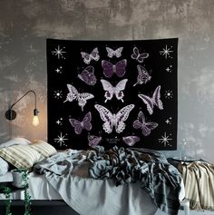 a bedroom with a bed covered in blankets and butterflies on the black wall above it