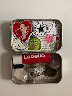 two tins filled with different types of items on a white surface and one has a sticker that says labella