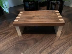 a wooden bench sitting on top of a hard wood floor next to potted plants